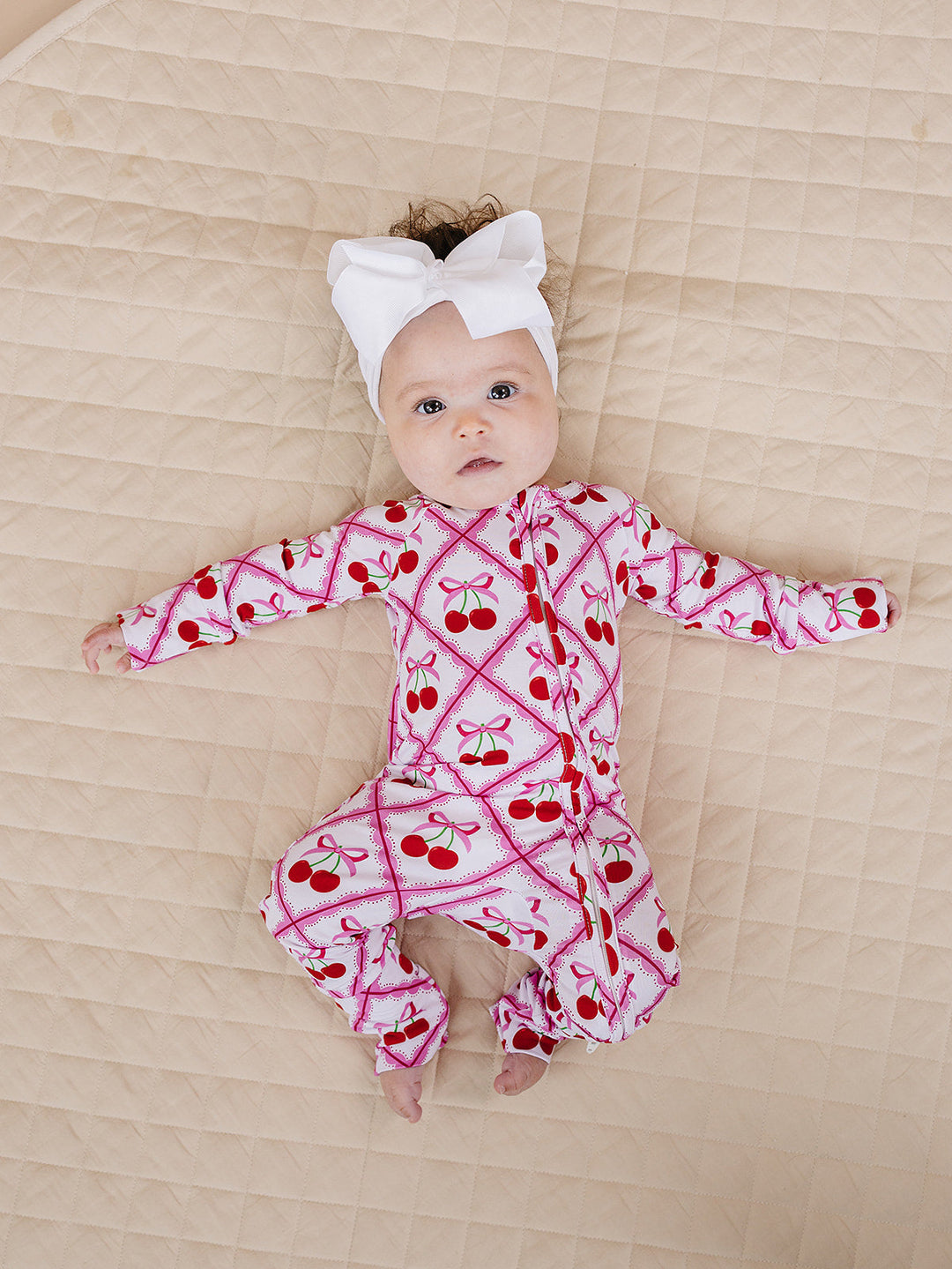 baby wearing a bubble romper with bare legs and sandals in a sunny outdoor setting