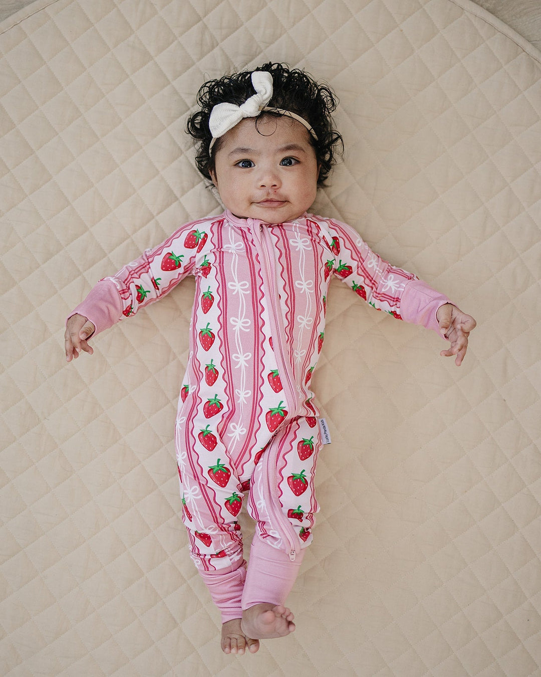 baby wearing a lightweight bamboo romper sitting on a blanket outdoors in warm weather