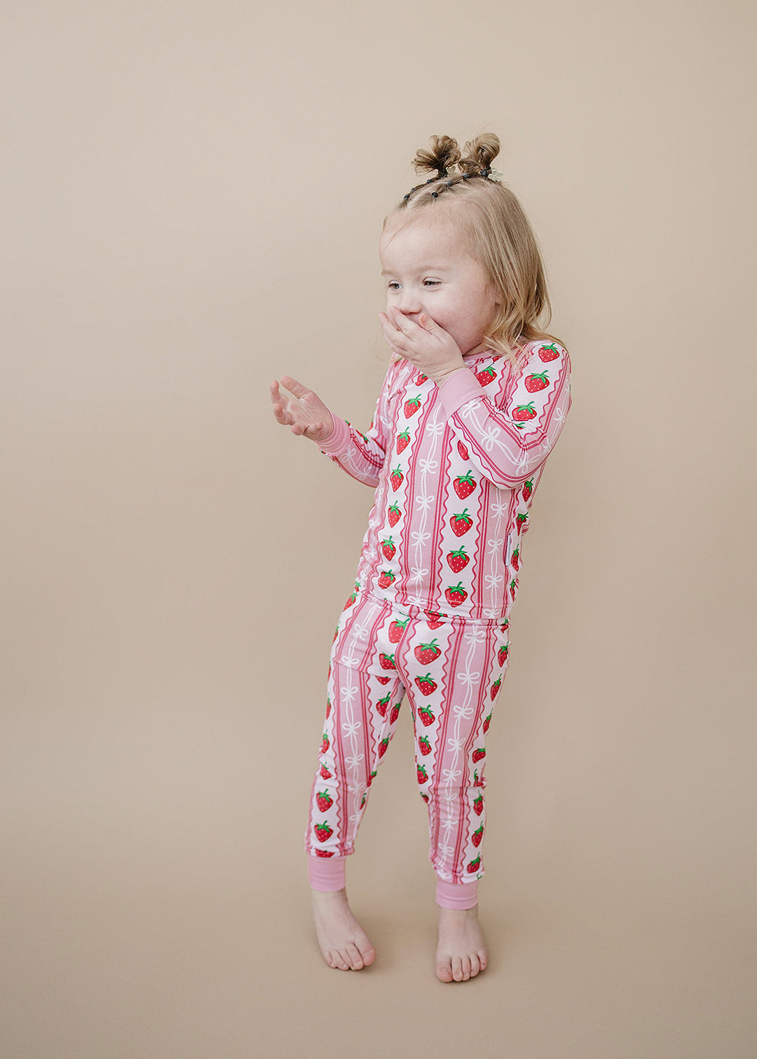 Baby wearing checkered flare pants with a white bodysuit sitting on a neutral rug