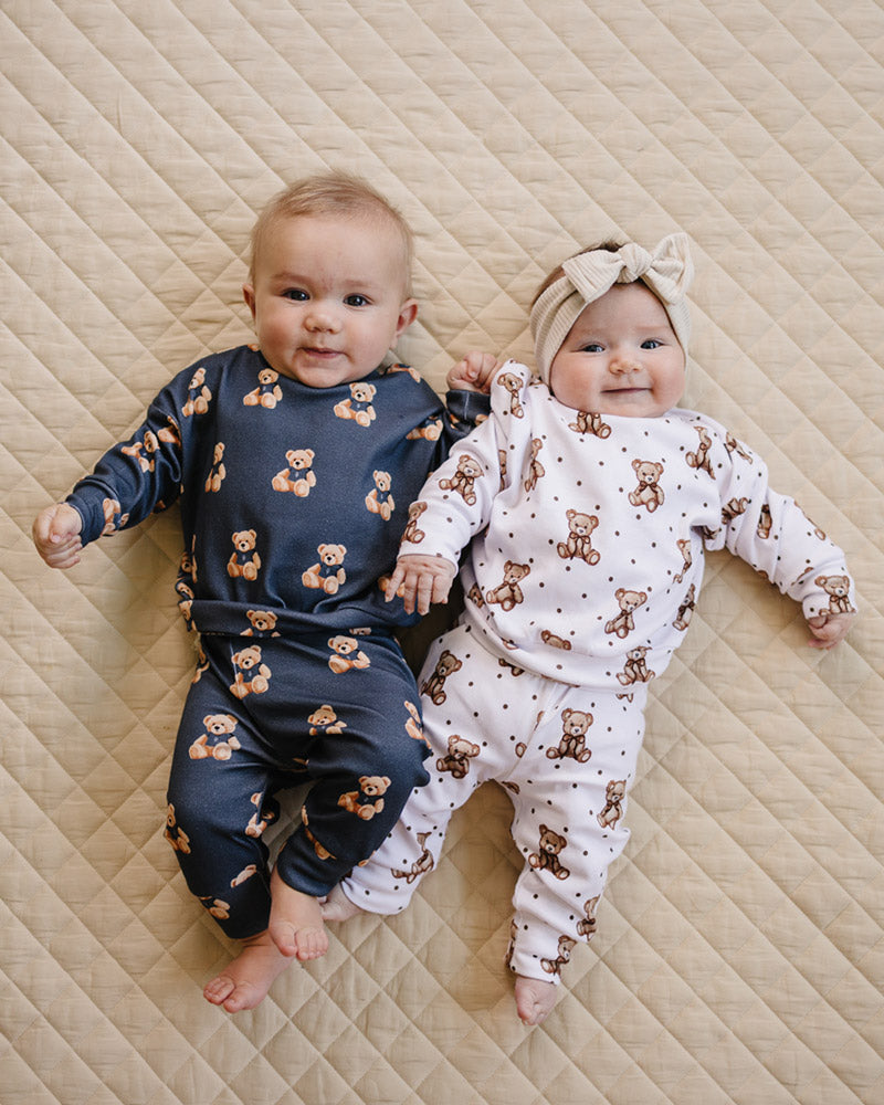 Close-up of two babies wearing coordinating Bear Vibes and Cute Bear teddy bear-print outfits.