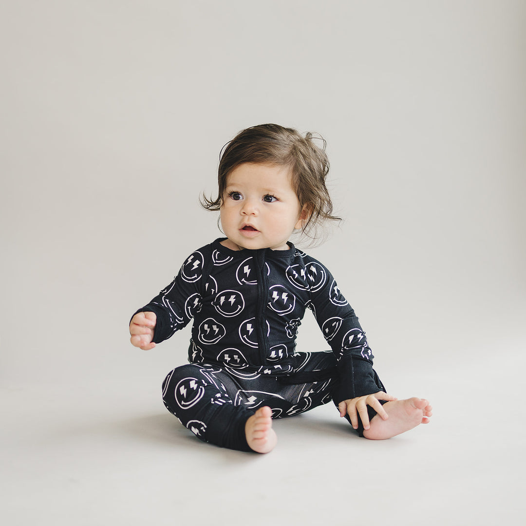 Little one wearing the Electric Smiley Bamboo Zip Romper with allover smiley face print