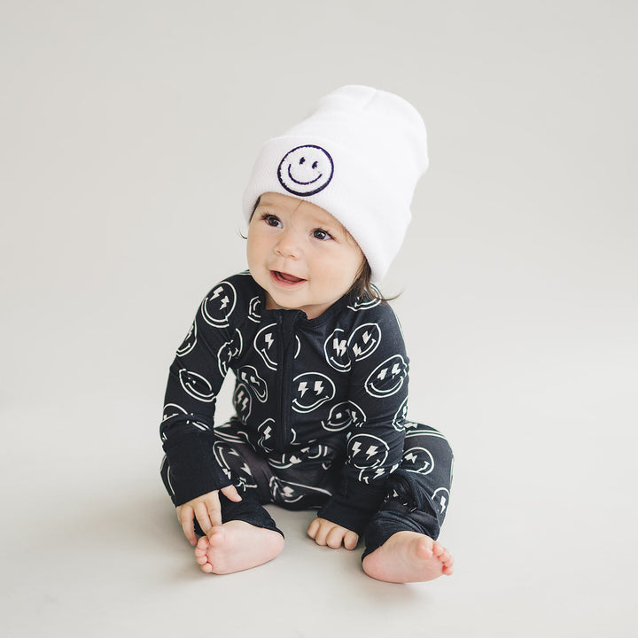 Baby sitting in the Electric Smiley Bamboo Zip Romper and smiley beanie