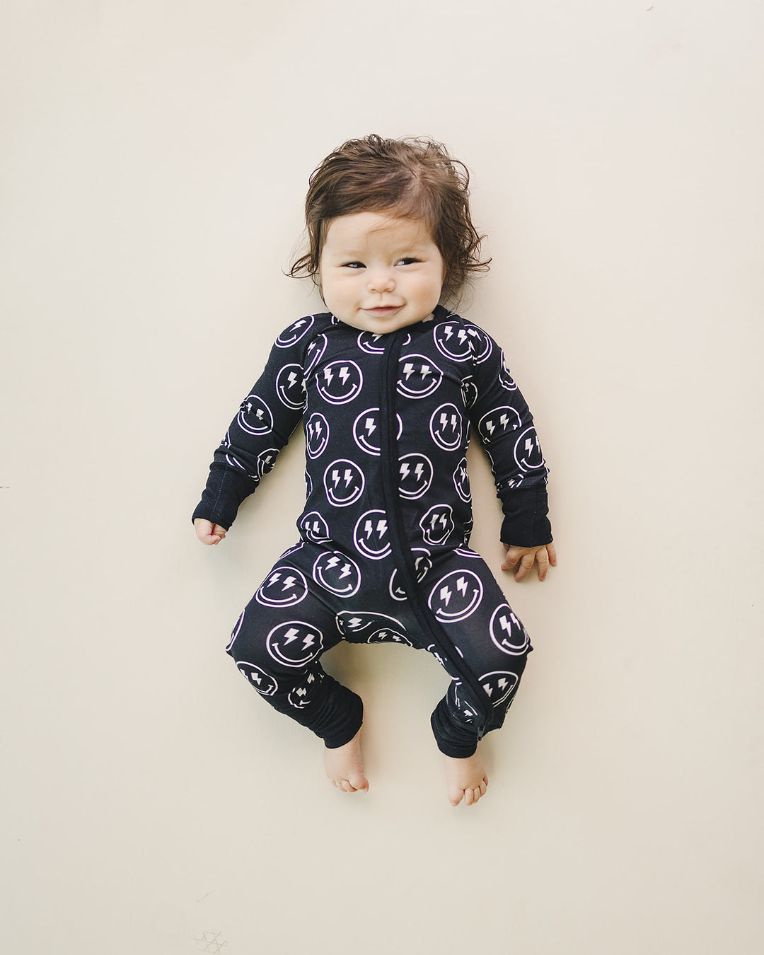 Little one relaxing in the Electric Smiley Bamboo Zip Romper