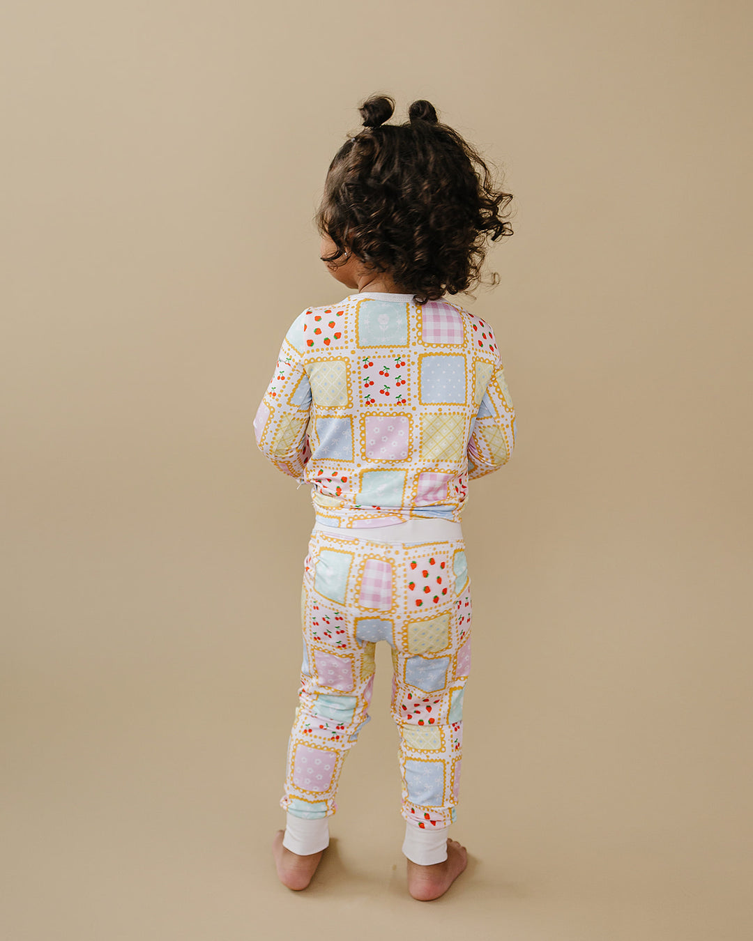 Back view of a toddler wearing Sweet Patchwork pajamas, showing the patchwork print across the top and pants.