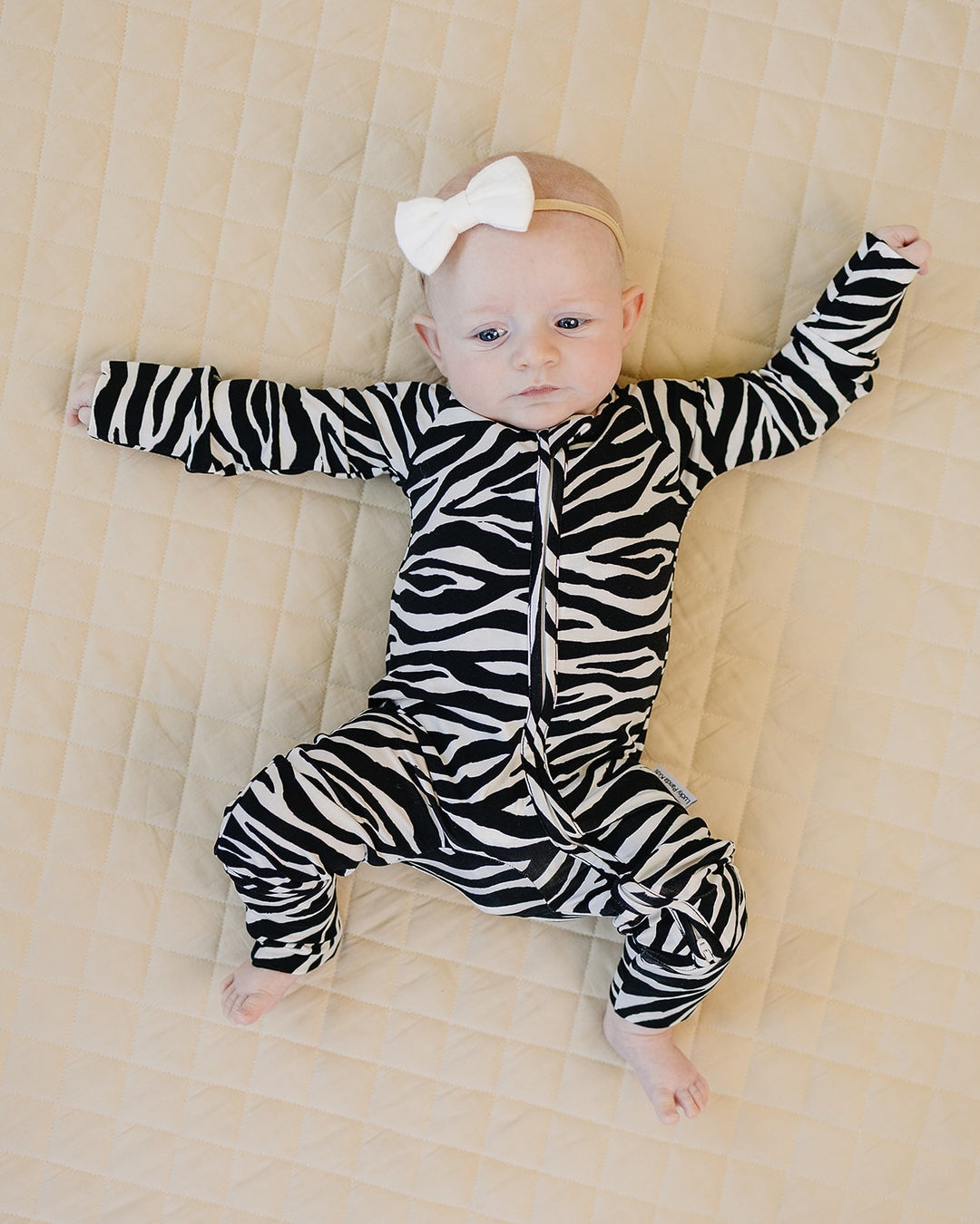 Baby relaxing in the Zebra Bamboo Zip Romper on a quilted blanket