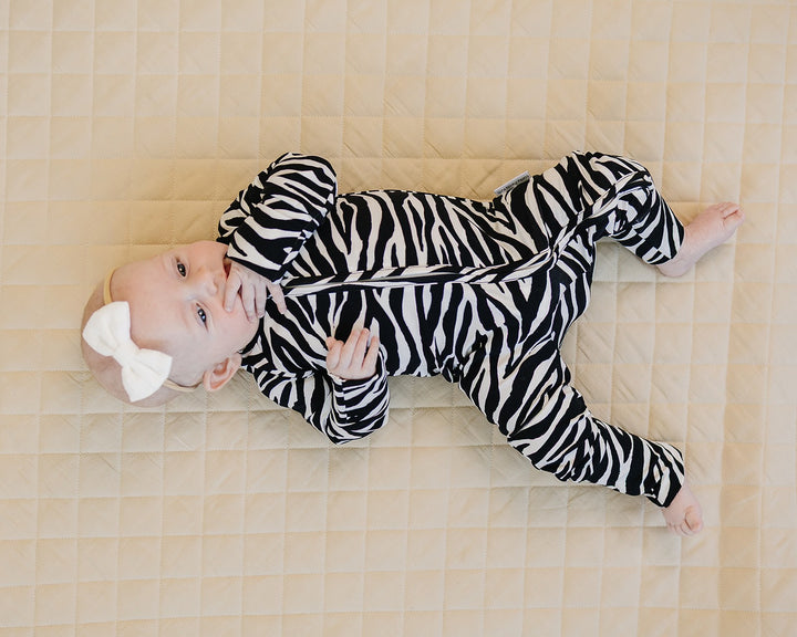 Baby lying in the Zebra Bamboo Zip Romper with black and white zebra print