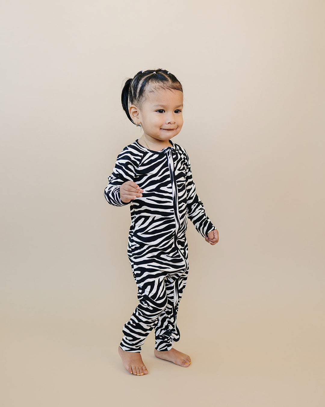 Little one standing in the Zebra Bamboo Zip Romper