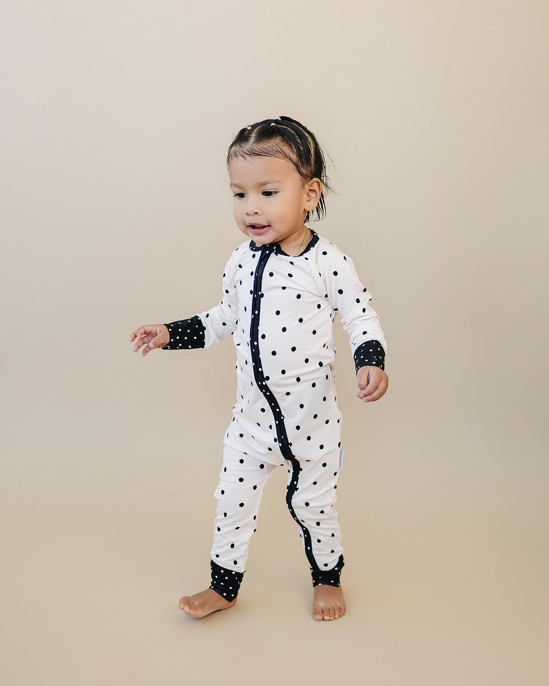 Little one standing in the Classic Polka Bamboo Zip Romper