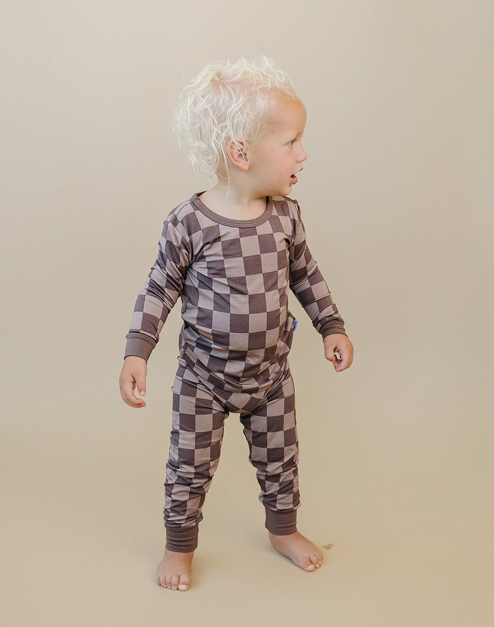 Toddler looking to the side in Espresso Checkered two piece pajamas with brown and taupe squares and brown cuffs.
