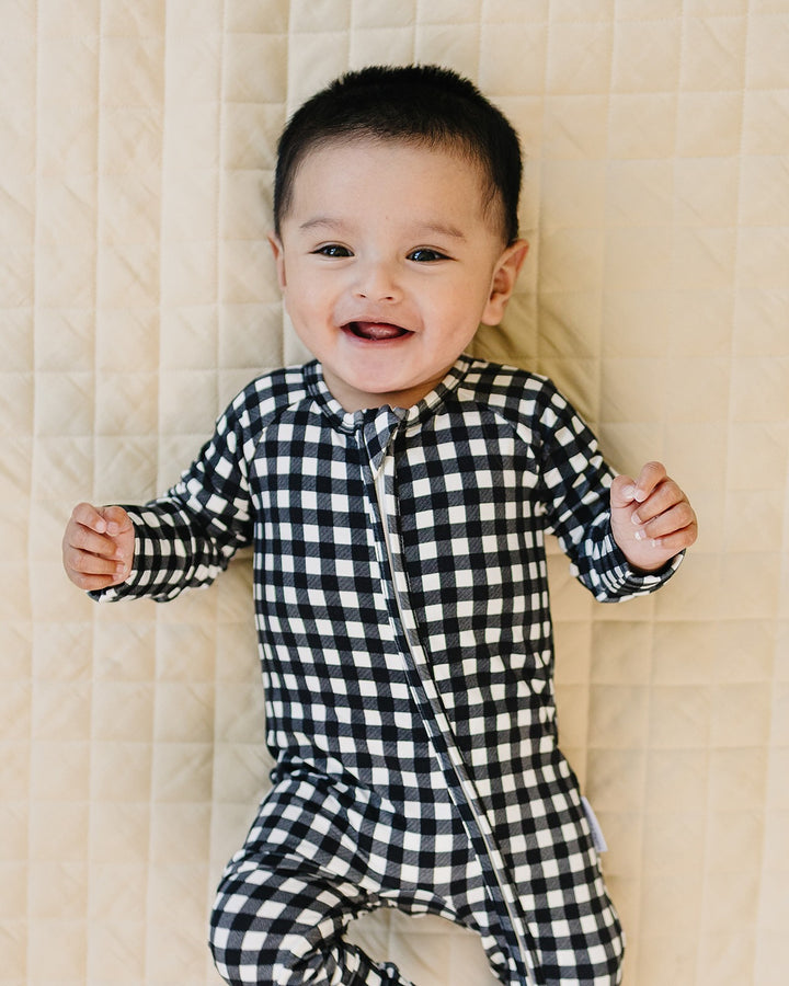 Baby relaxing in the Black Gingham Bamboo Zip Romper with black and white check print
