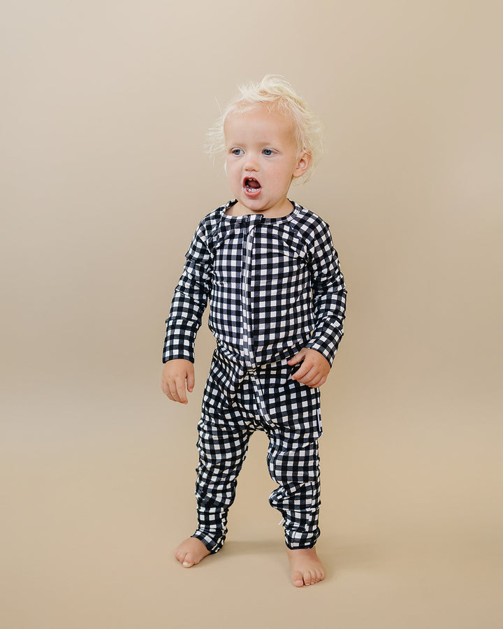 Front view of little one wearing the Black Gingham Bamboo Zip Romper