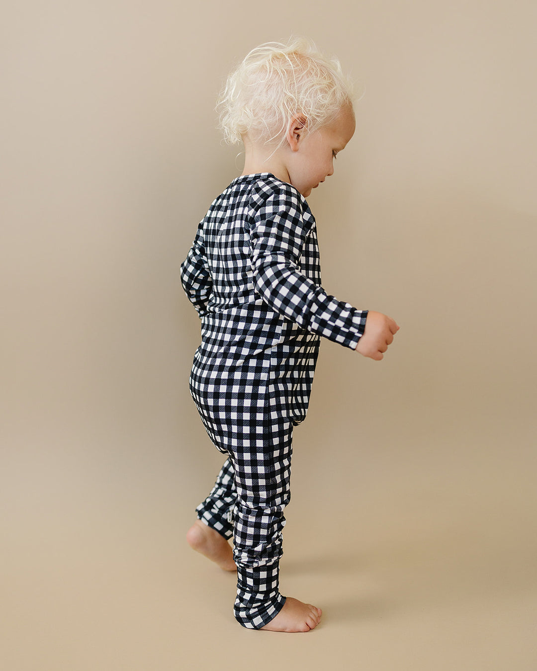 Back and side view of little one wearing the Black Gingham Bamboo Zip Romper
