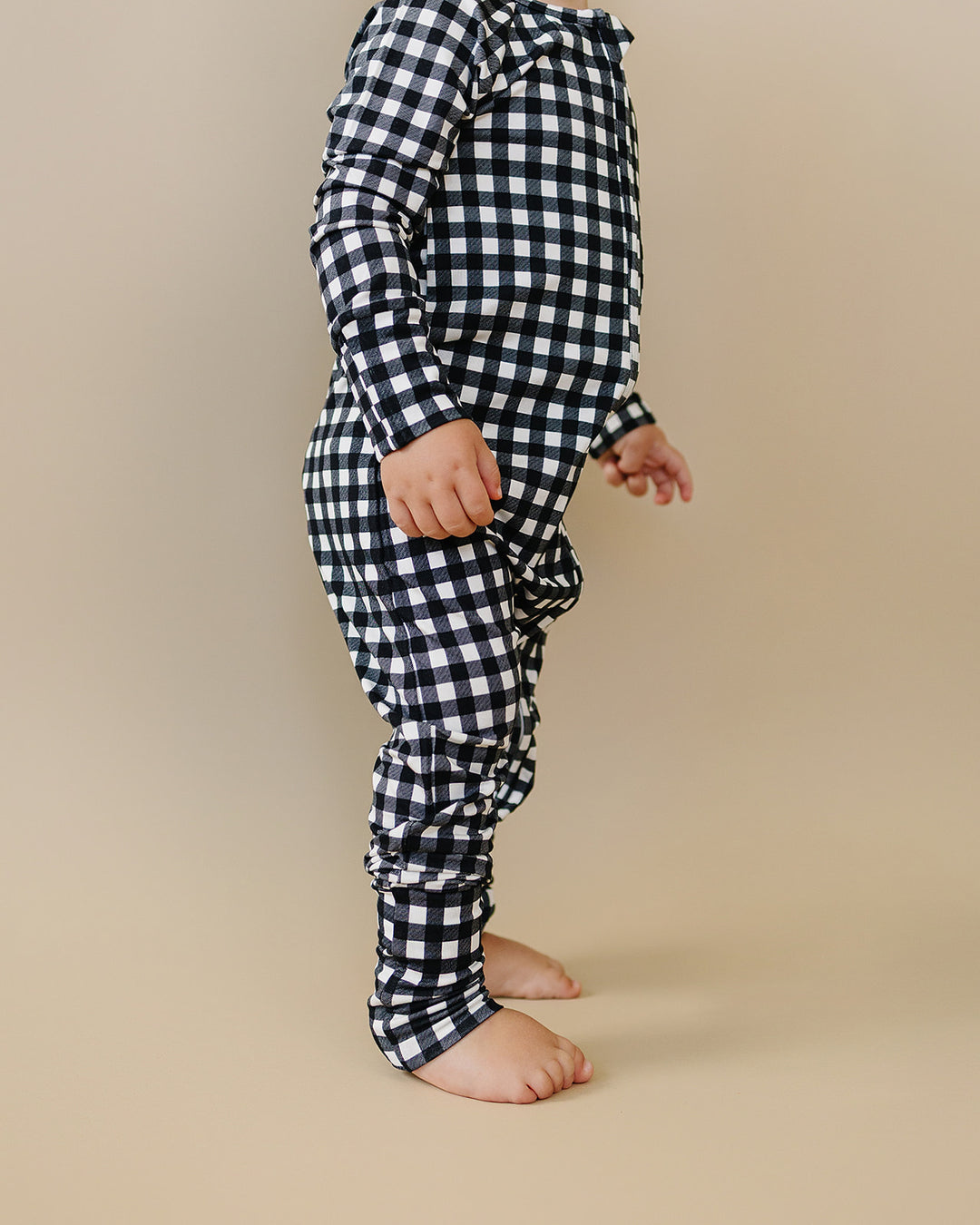 Side view of little one wearing the Black Gingham Bamboo Zip Romper