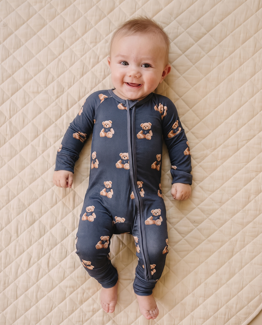 Smiling baby modeling the Bear Vibes bamboo zip romper with convertible footies.