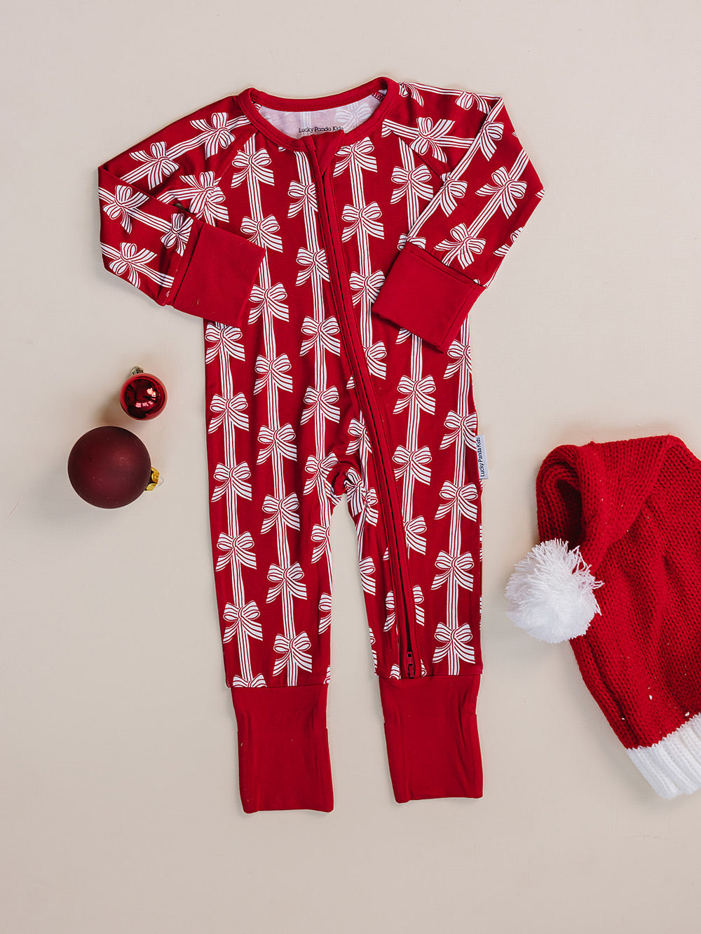 Red Bows Bamboo Zippy — red bow-print Christmas romper flat lay Lucky Panda Kids