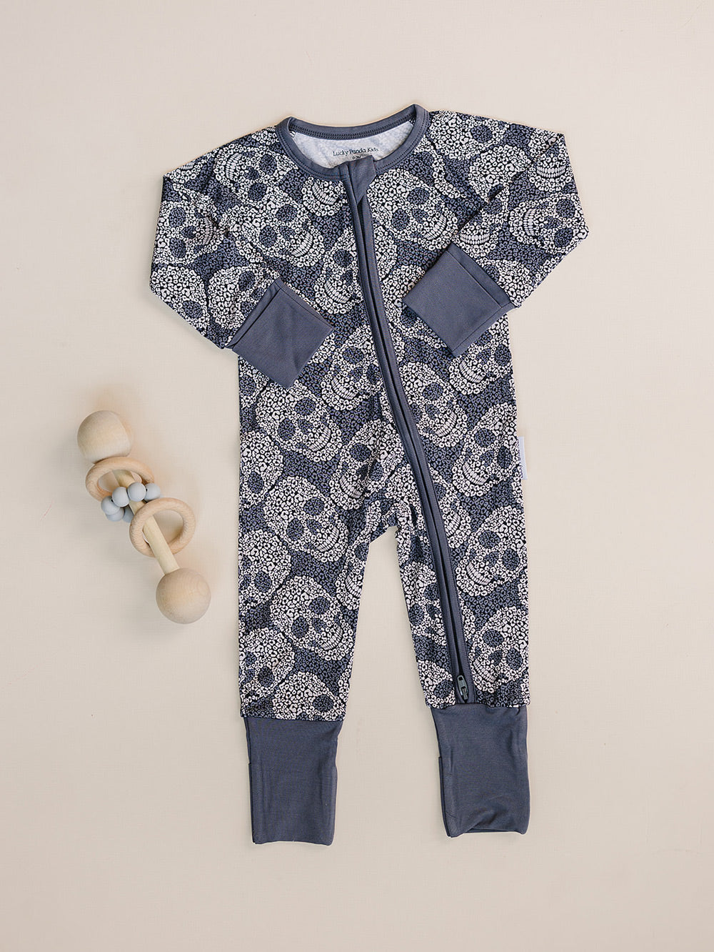 Leopard Skull Bamboo Zip Romper displayed flat with a wooden baby toy.