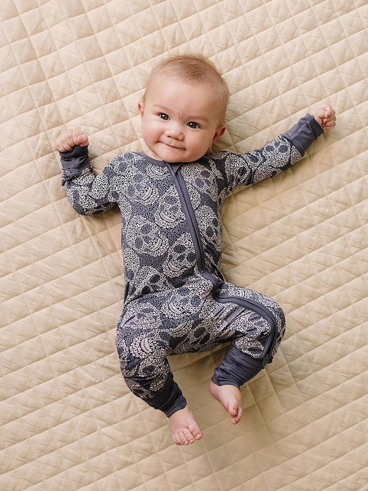 Baby wearing the grey Leopard Skull Halloween Bamboo Zip Romper on a quilted blanket.