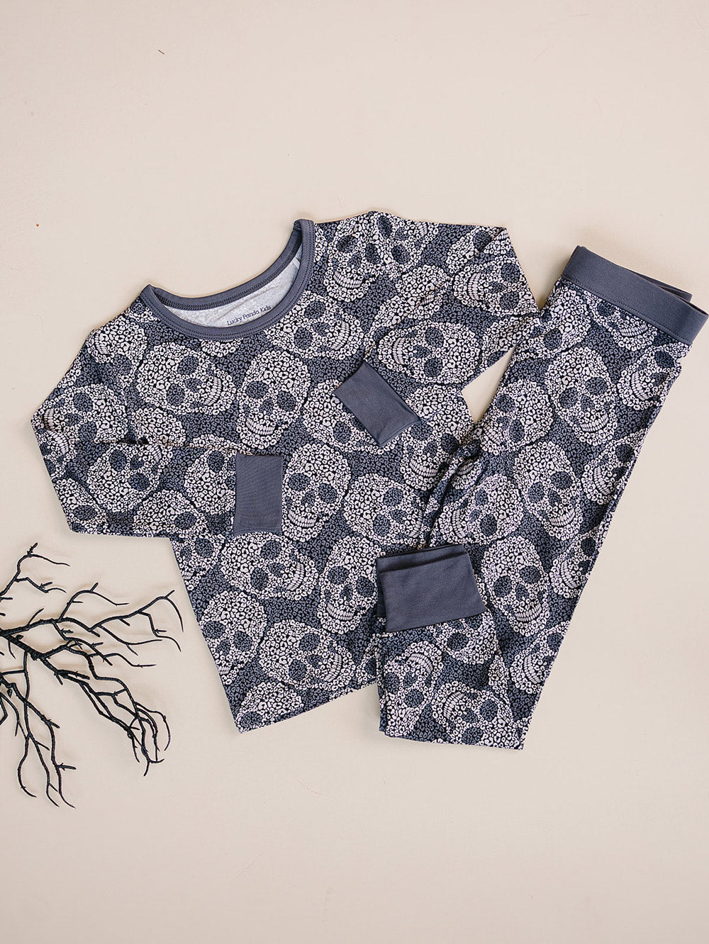 Leopard Skull Halloween Bamboo Pajama Set displayed flat with dried branch decor.