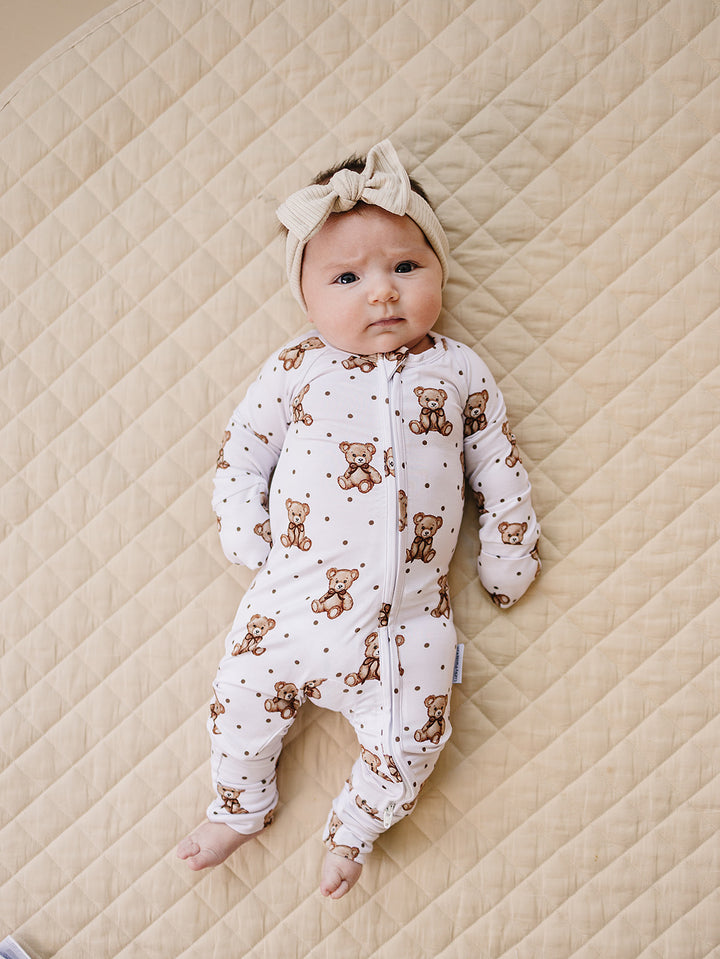 Baby wearing the Cute Bear bamboo romper while lying on a cream quilted mat.