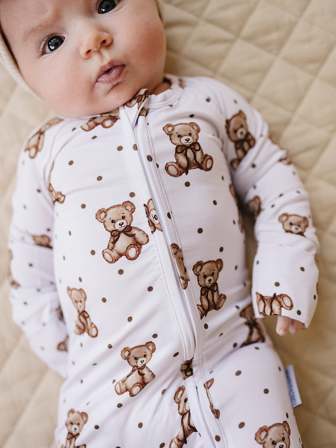 Close-up of a baby wearing the white teddy bear-print bamboo zip romper.