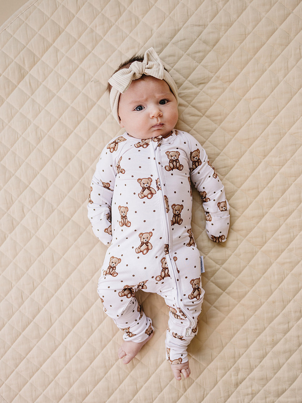 Baby modeling the Cute Bear zip romper with convertible footies on a quilted mat.