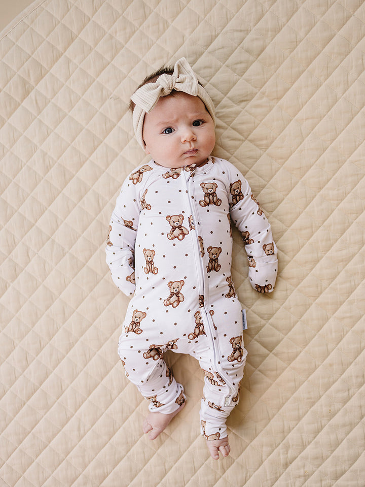 Baby modeling the Cute Bear zip romper with convertible footies on a quilted mat.