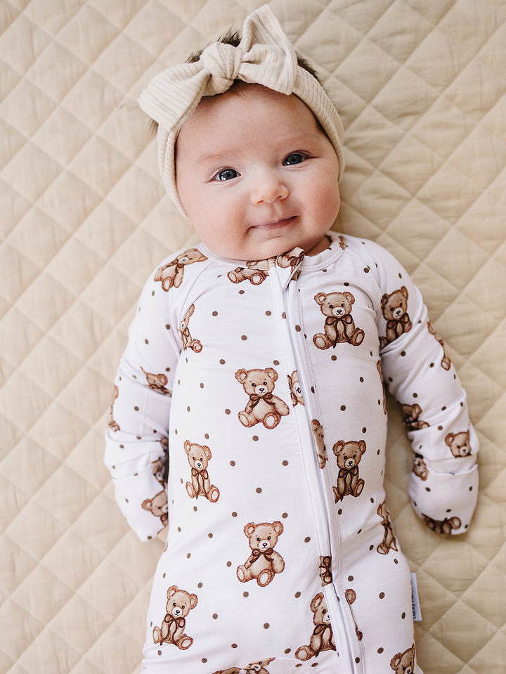 Baby modeling the Cute Bear bamboo romper with a matching bow headband.