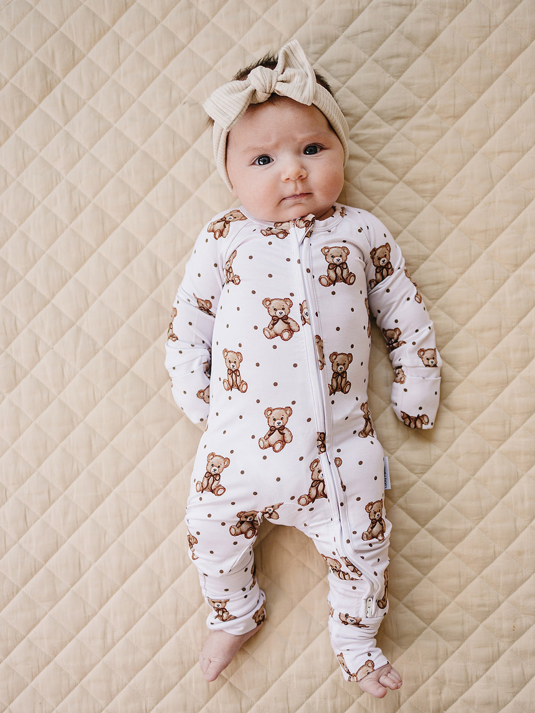 Baby modeling the Cute Bear zip romper with convertible footies on a quilted mat.
