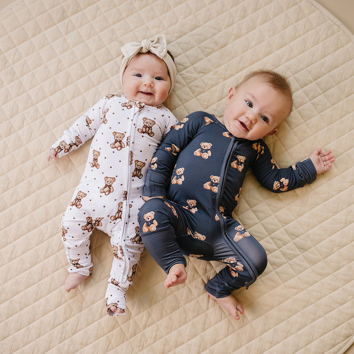 Two babies lying together in coordinating dark charcoal and Cute bear bamboo rompers.