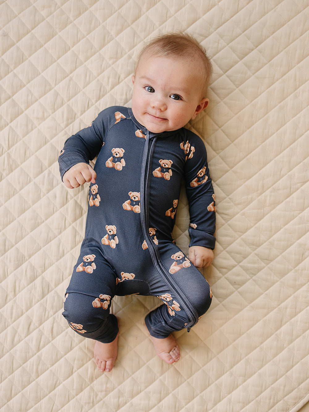 Baby wearing the dark charcoal Bear Vibes bamboo zip romper on a cream quilted mat.