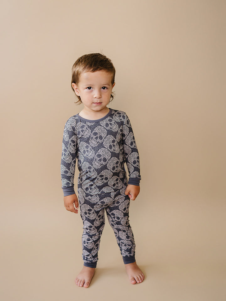Toddler standing and smiling in the grey Leopard Skull Bamboo Pajama Set.