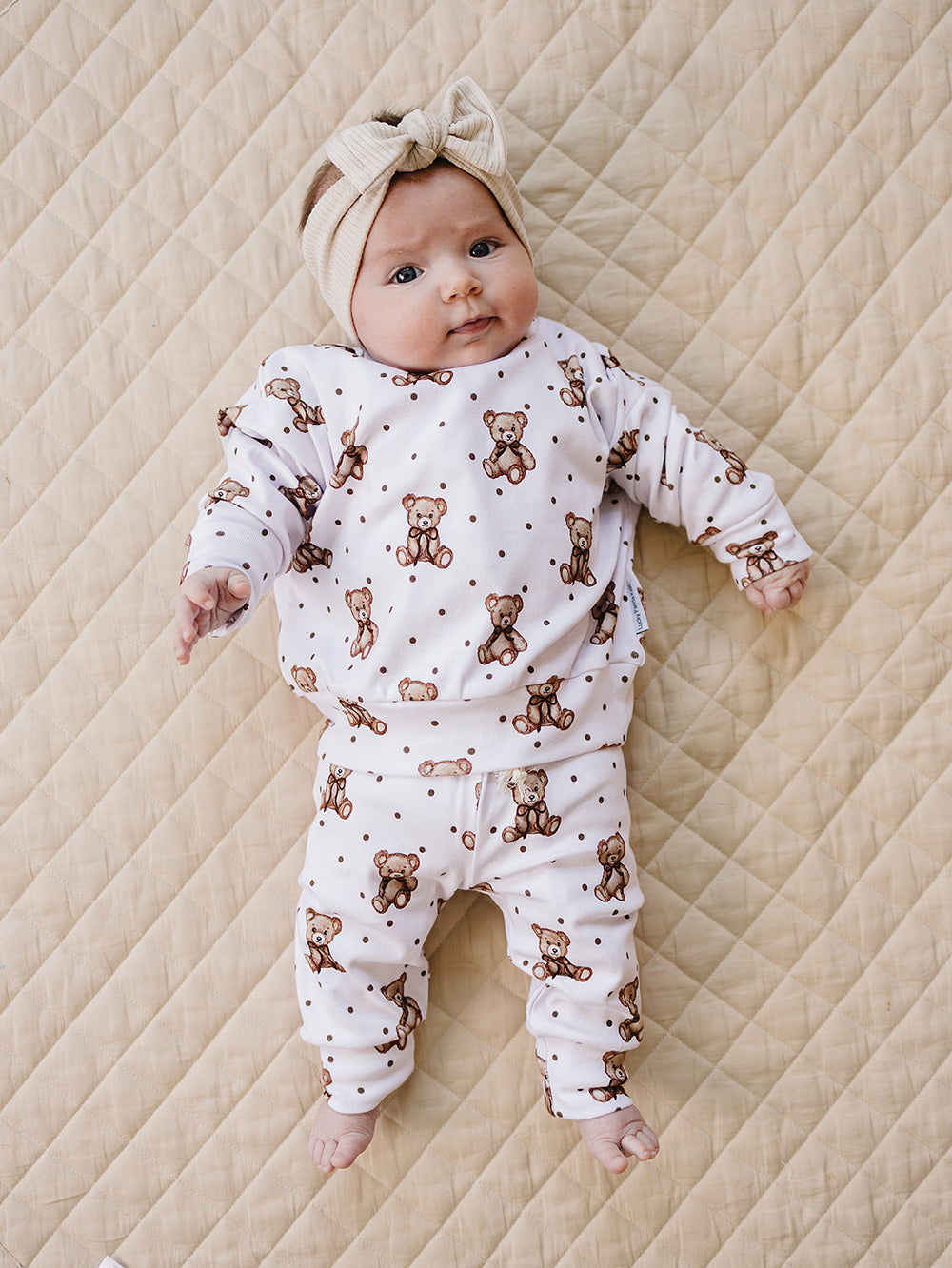Full-length view of a baby wearing the white teddy bear-print jogger set.
