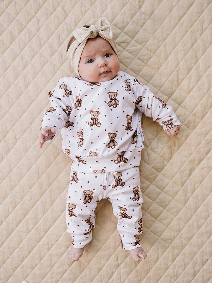 Full-length view of a baby wearing the white teddy bear-print jogger set.
