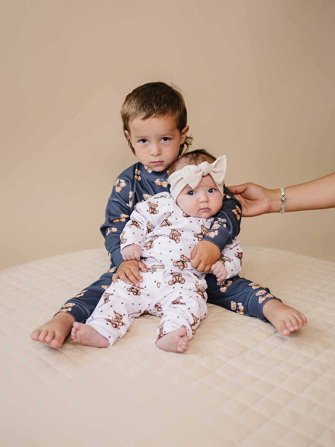Child holding a baby dressed in the Cute Bear teddy bear-print outfit.