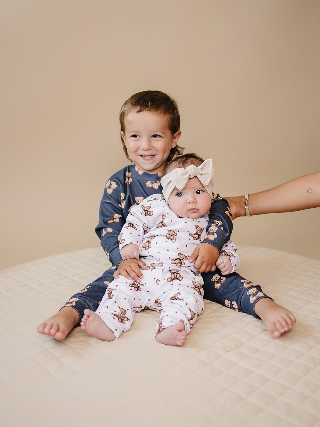 Child wearing the Bear Vibes jogger set while sitting with a baby in a coordinating bear-print outfit.