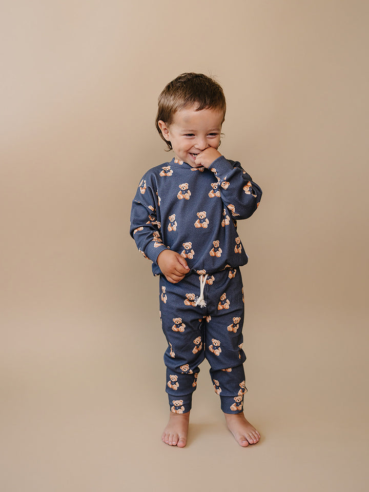 Full-length view of a toddler wearing the dark charcoal teddy bear-print jogger set.