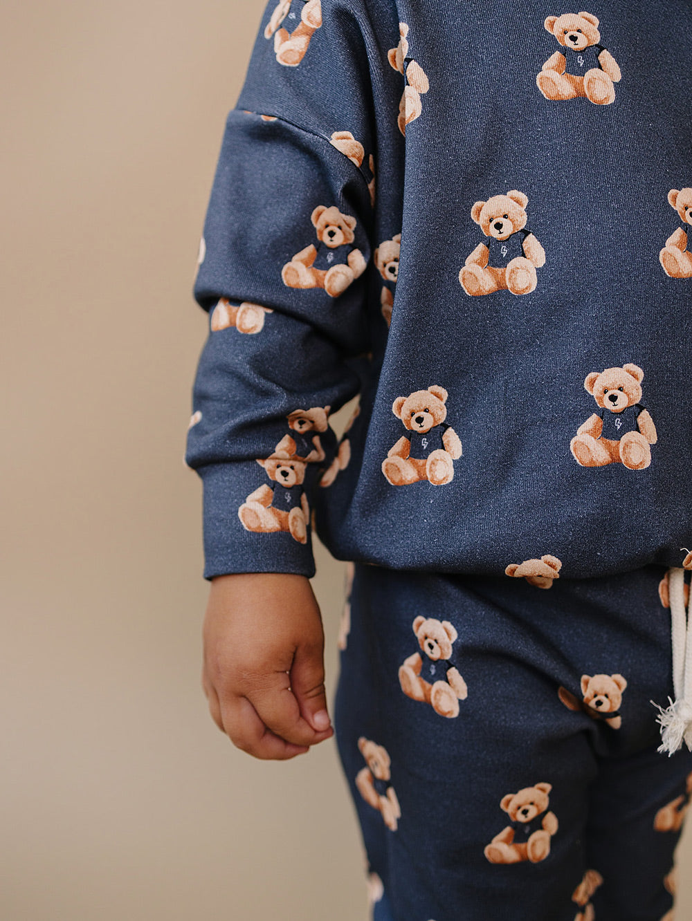 Close-up of the teddy bear print, crewneck top, and matching jogger pants.