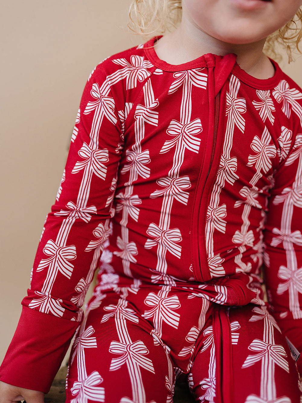 Red Bows Bamboo Zippy — baby girl in red bow-print Christmas romper, zoom in Lucky Panda Kids