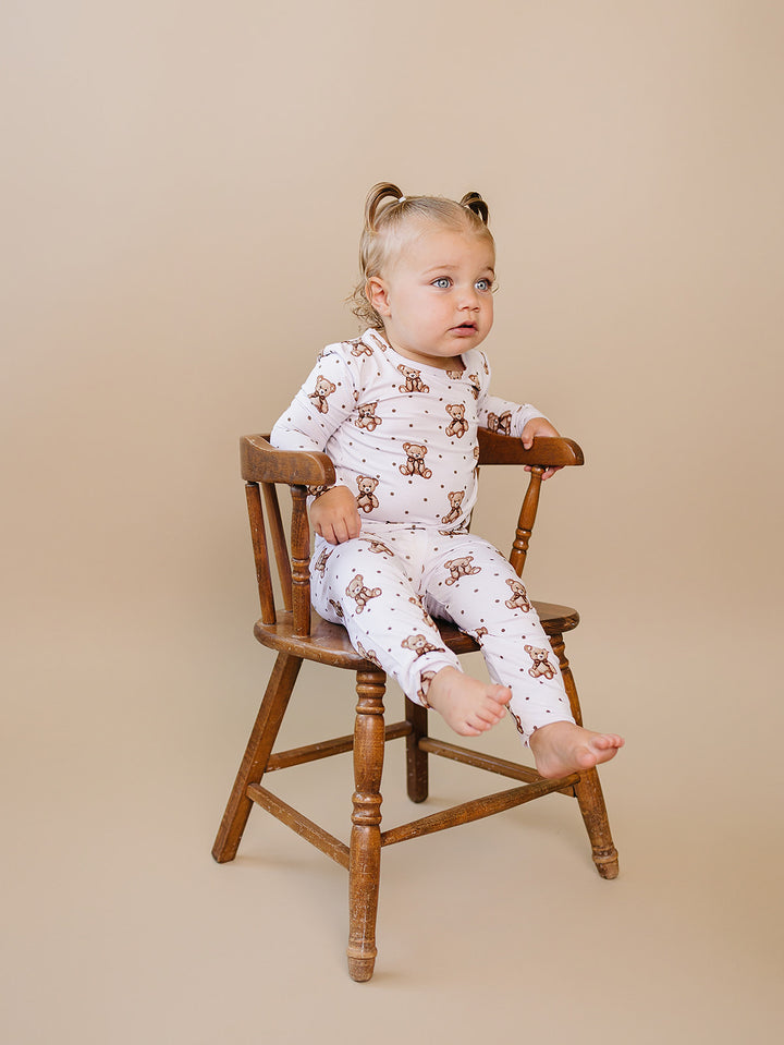 Toddler sitting on a wooden chair while modeling the Cute Bear bamboo outfit.