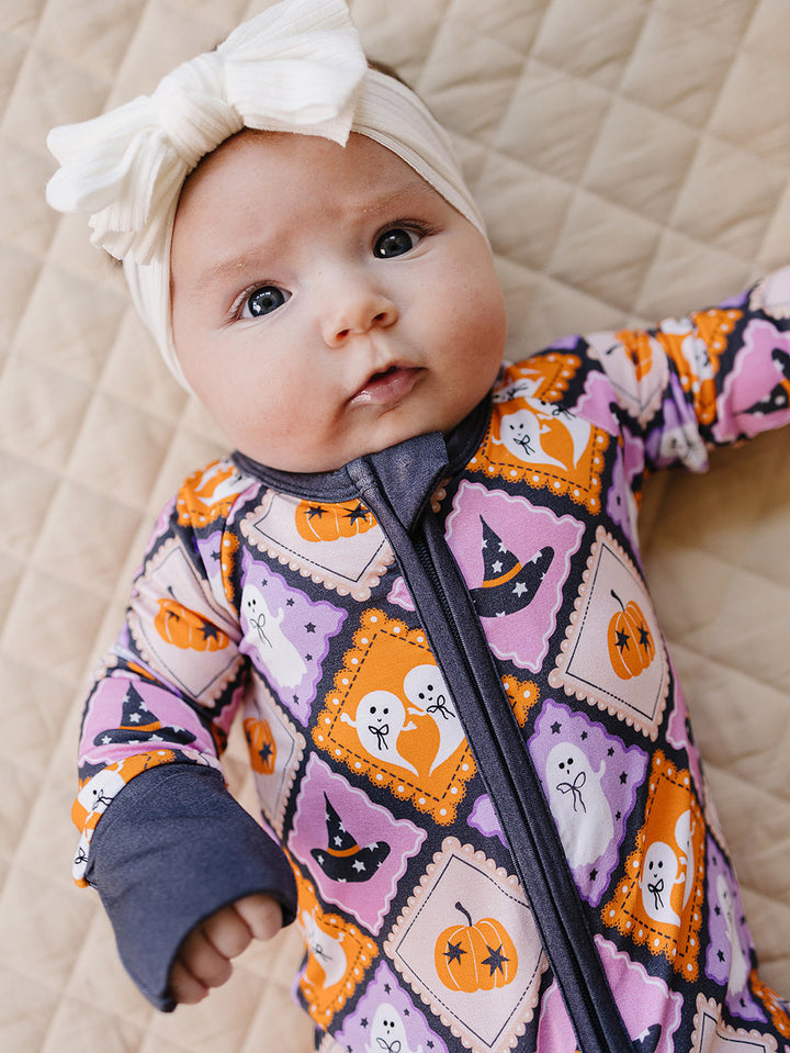 Close-up of a baby wearing the Ghost Whimsy bamboo romper and a bow headband.