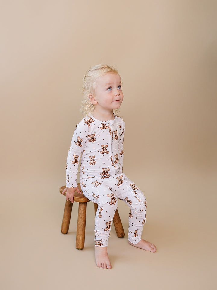 Toddler seated on a wooden stool wearing the Cute Bear bamboo romper.