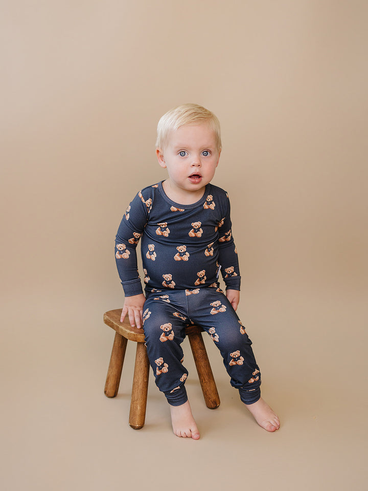 Toddler sitting on a wooden stool in the Bear Vibes bamboo two-piece outfit.