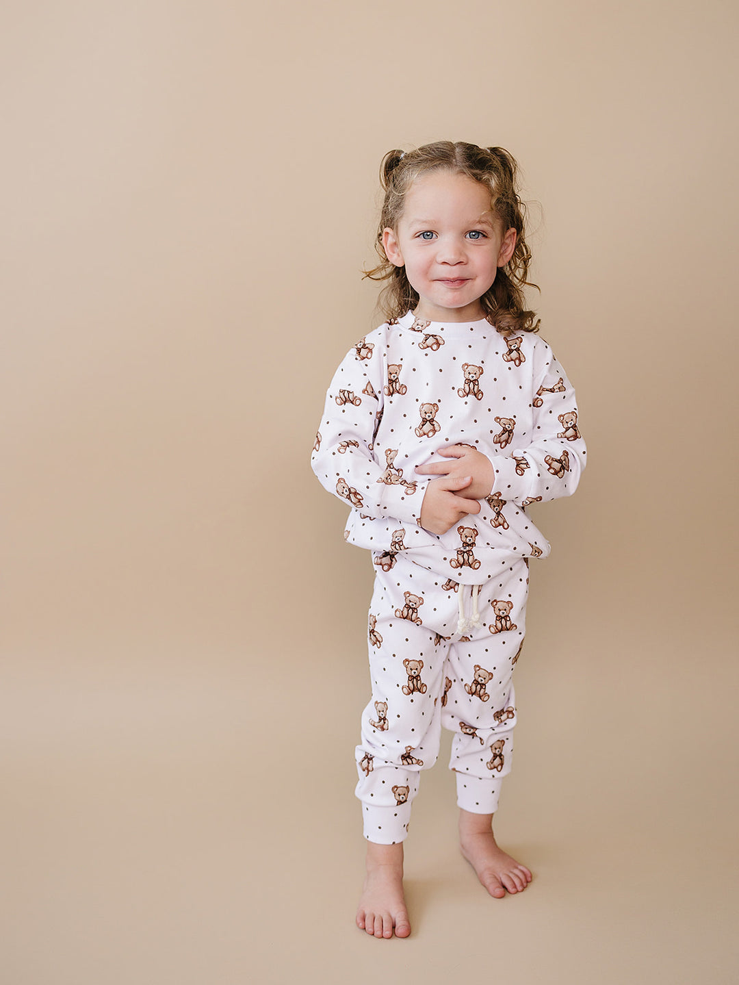 Full-length view of a toddler walking in the white Cute Bear jogger set.
