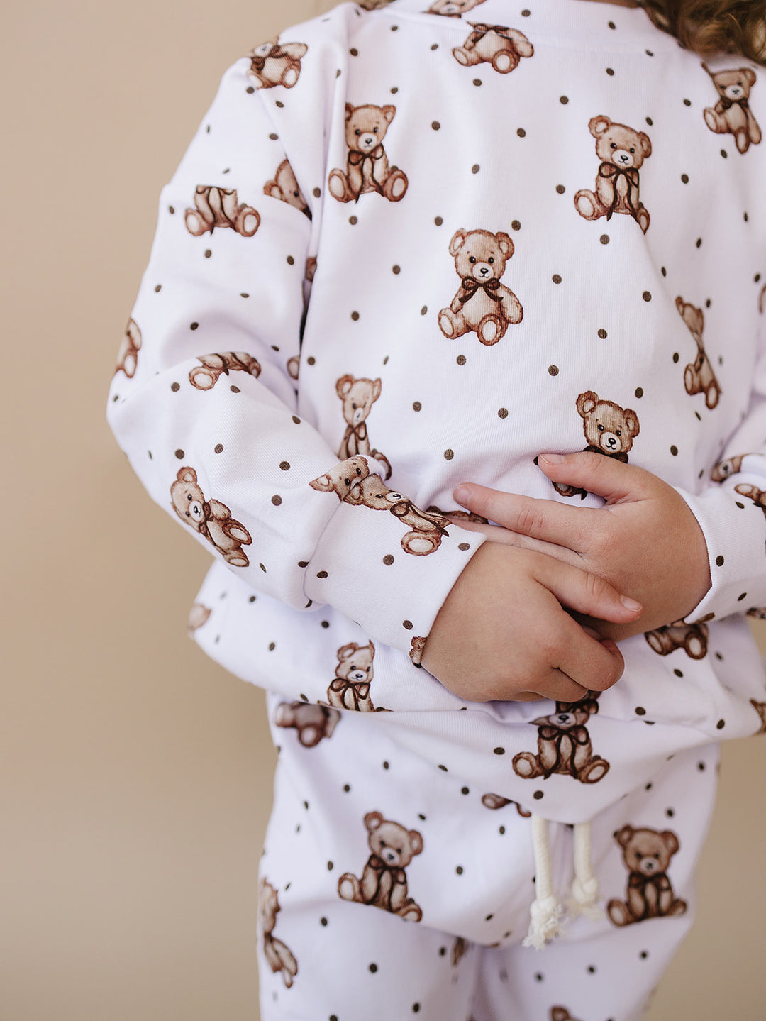 Close-up of the teddy bear print, crewneck top, and faux drawstring waistband.
