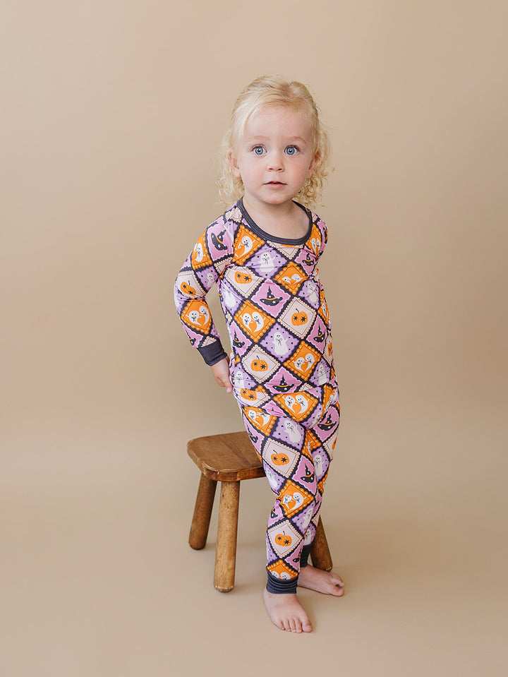 Toddler posing beside a wooden stool in the Ghost Whimsy Halloween pajama set.