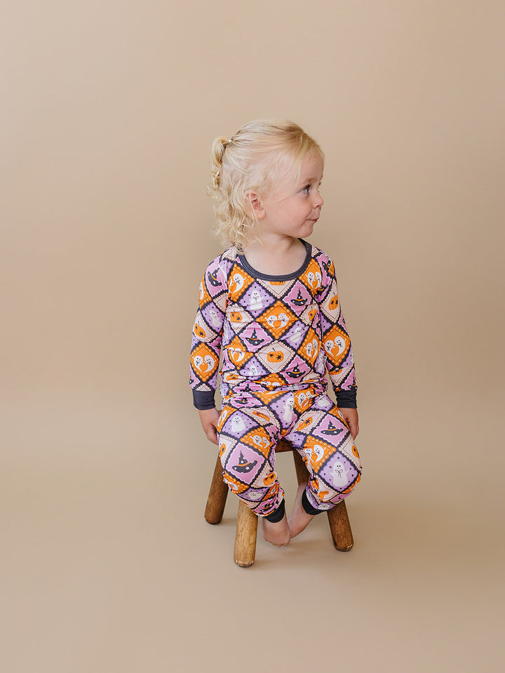 Toddler standing beside a wooden stool in the Ghost Whimsy bamboo pajama set.