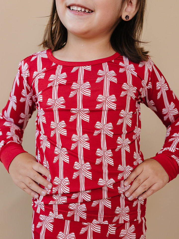  Red Bows Bamboo Two Piece — toddler girl in red bow-print Christmas pajama set, close up Lucky Panda Kids

