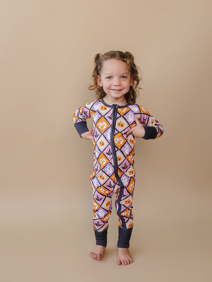 Full-length view of a toddler girl wearing the Ghost Whimsy Bamboo Zip Romper.