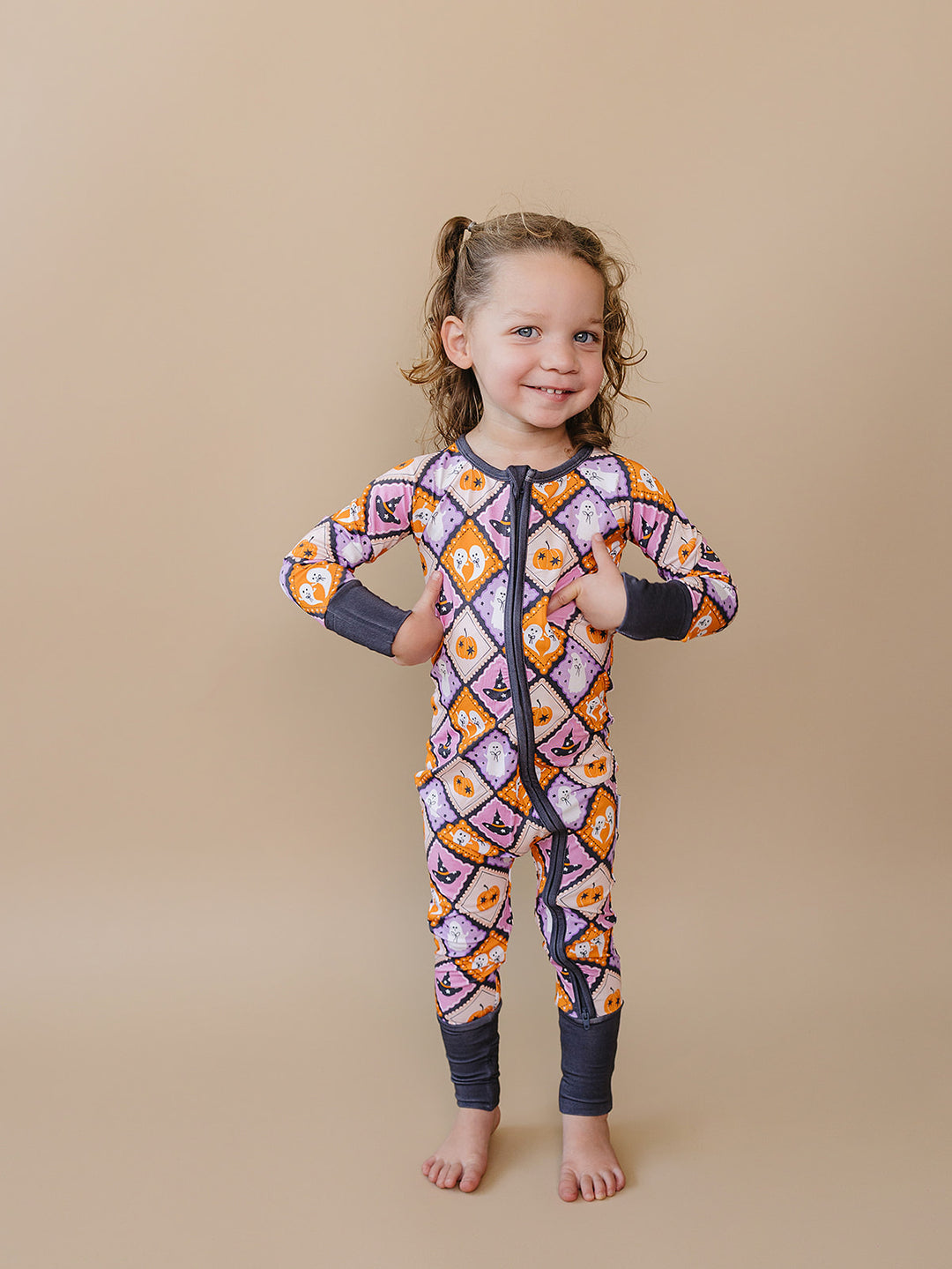 Smiling toddler girl wearing the Ghost Whimsy Bamboo Zip Romper.