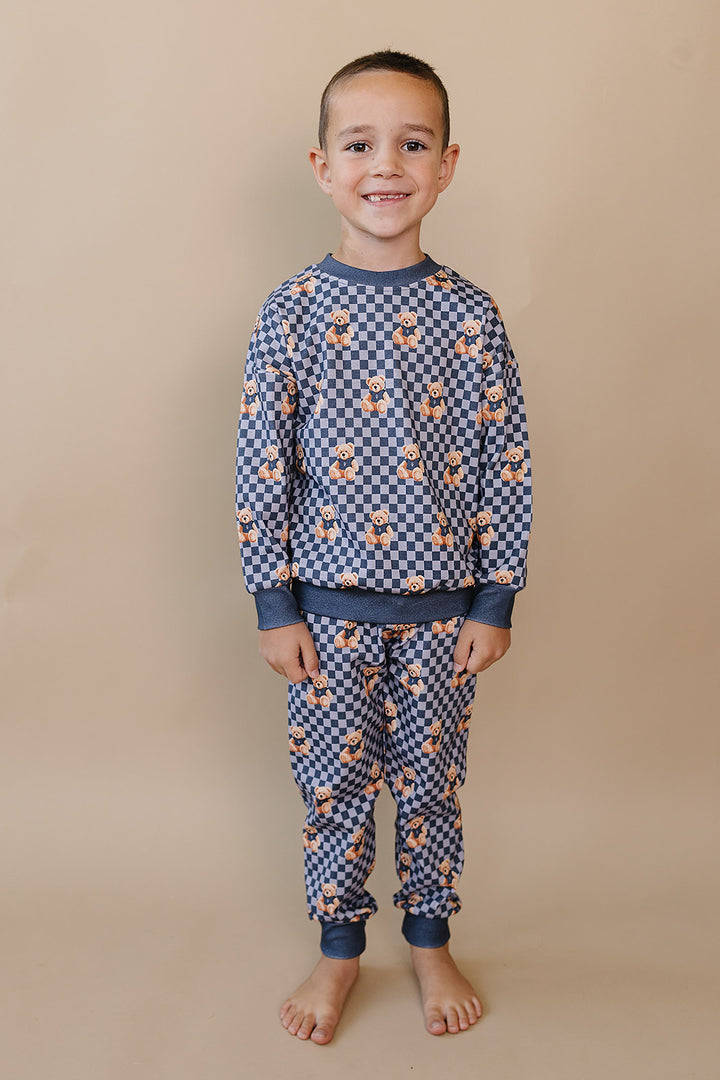 Full-length front view of a child modeling the blue Checkered Bear Vibes jogger set.